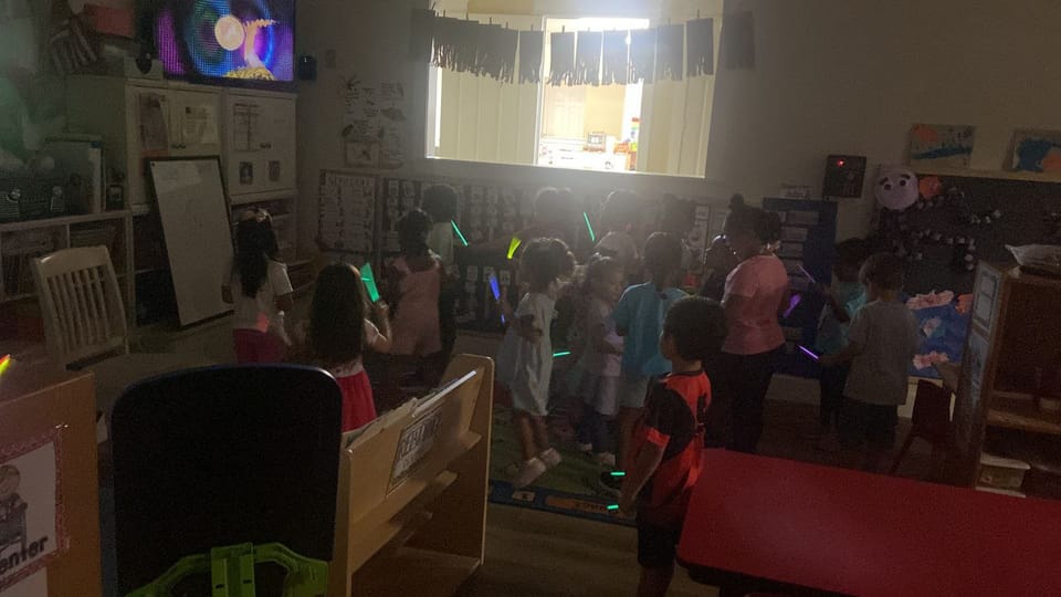 Kids dancing together with colorful glow sticks during the glow stick party.