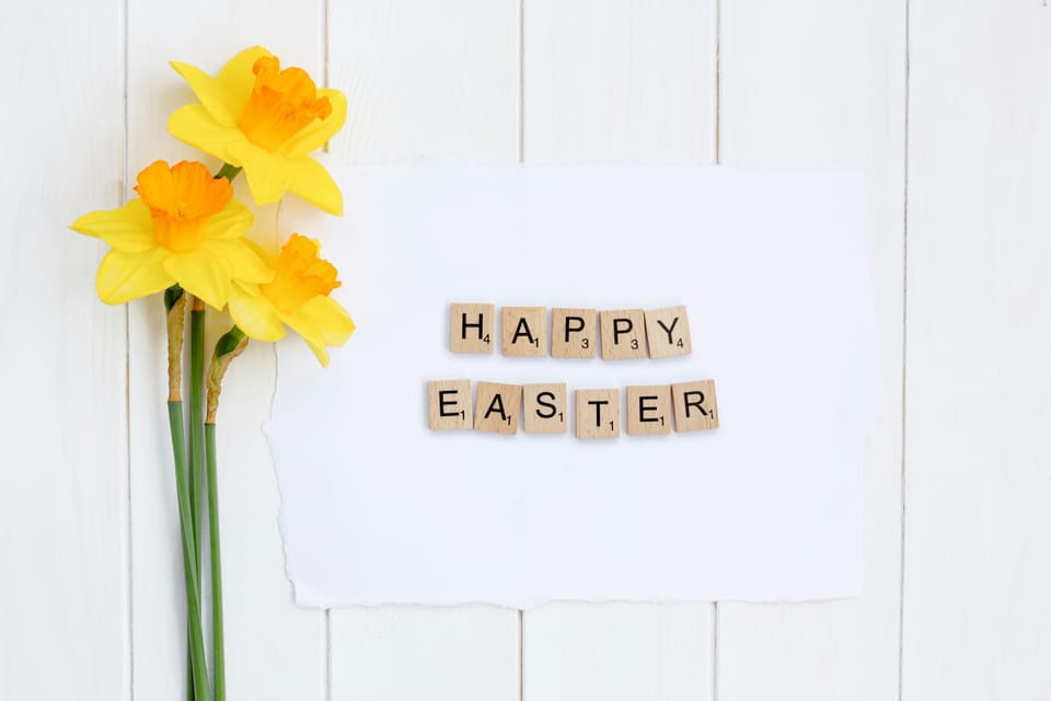 Yellow daffodils beside letter tiles spelling "Happy Easter."