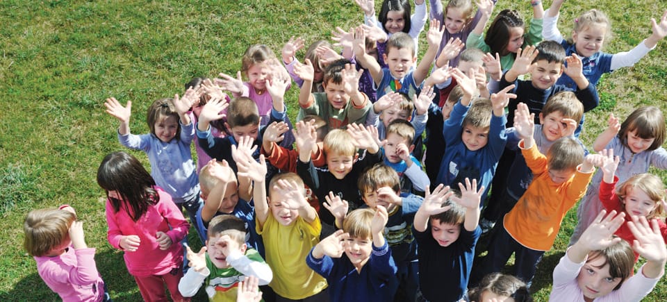 A crowd of children looking way up at the camera.